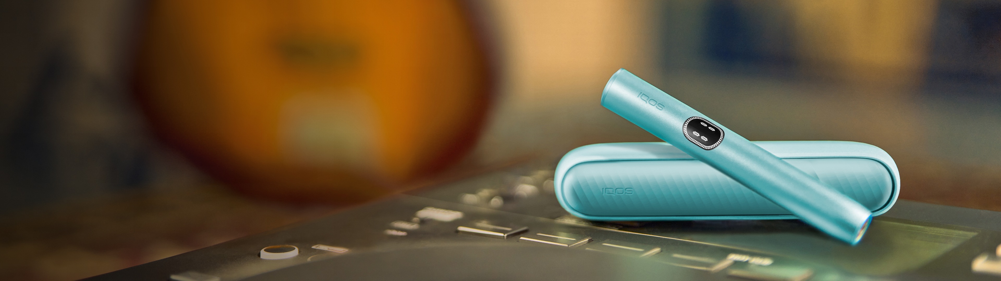 IQOS ILUMA i device in Breeze Blue color in a blurred background.