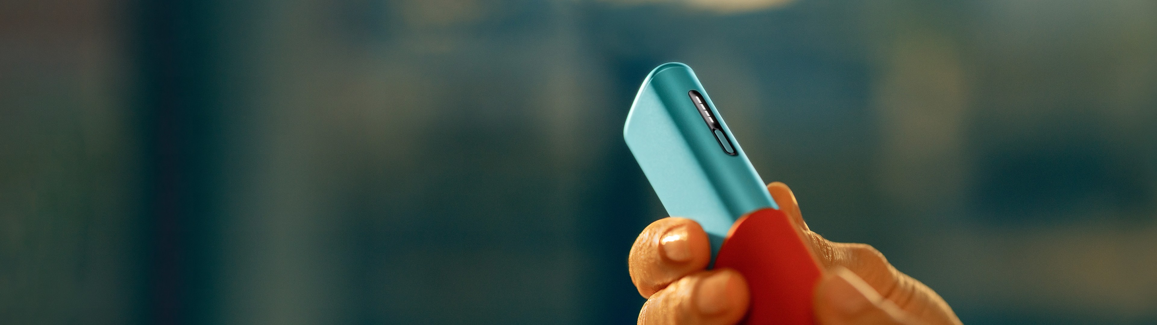 A hand holding an IQOS ILUMA i ONE device in Breeze Blue color.