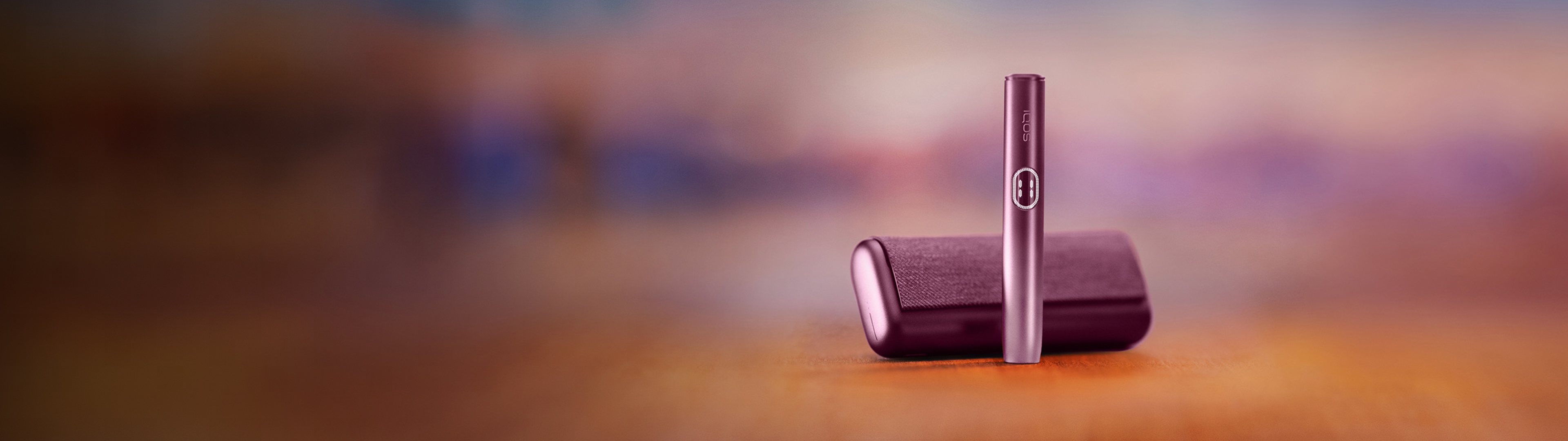 IQOS ILUMA i PRIME device in Garnet Red color in a purple blurred background.