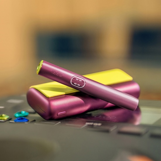 IQOS ILUMA i PRIME device in Garnet Red color with yellow accessories.