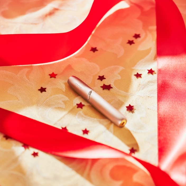Brilliant gold IQOS 3 DUO holder inserted on fabric with red stars
