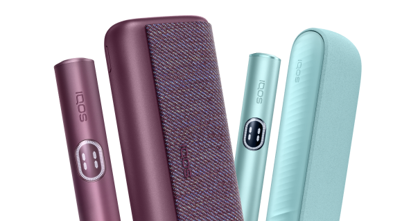 Du IQOS ILUMA i PRIME įrenginiai turkio spalvos fone.