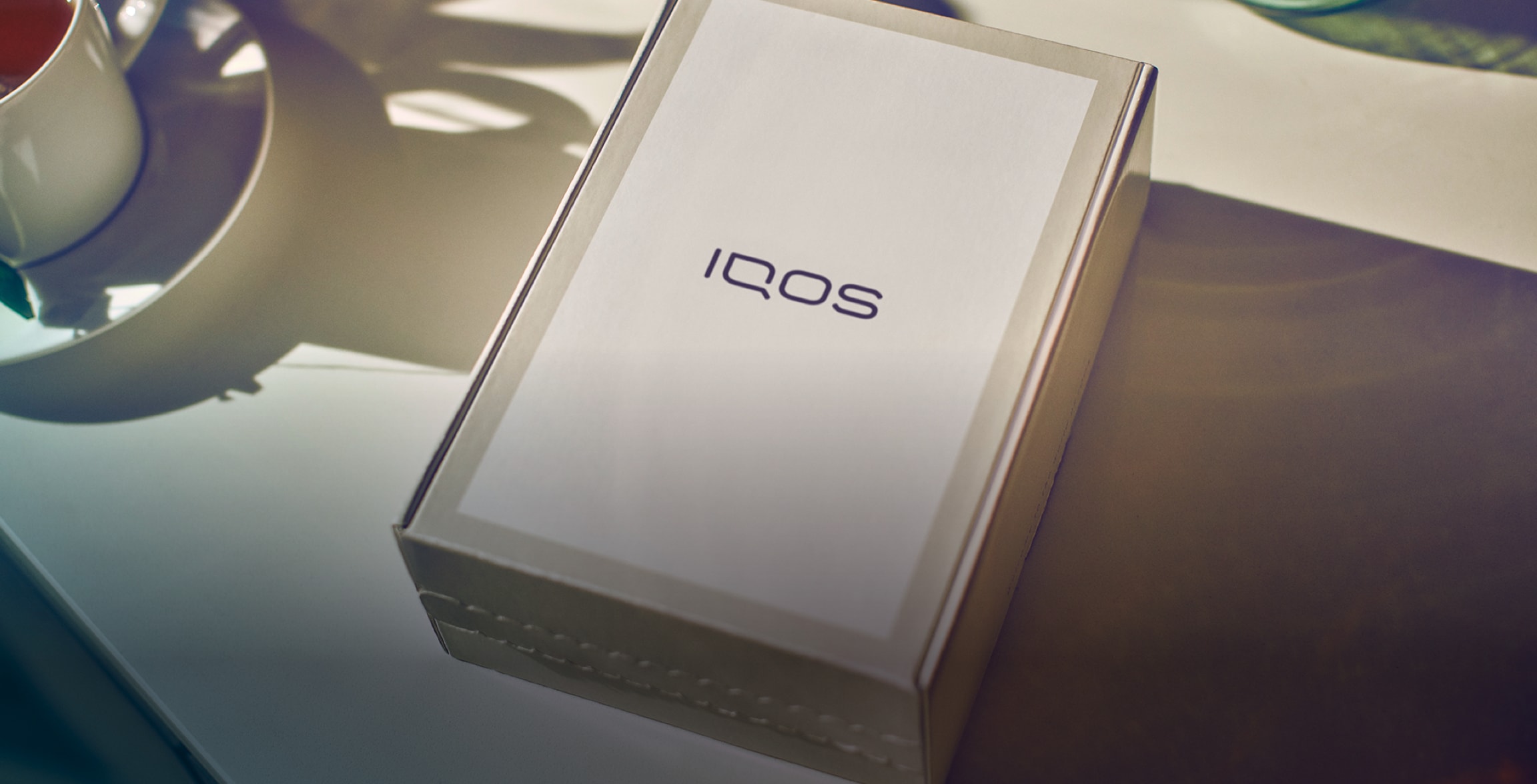 Hands holding an IQOS box.