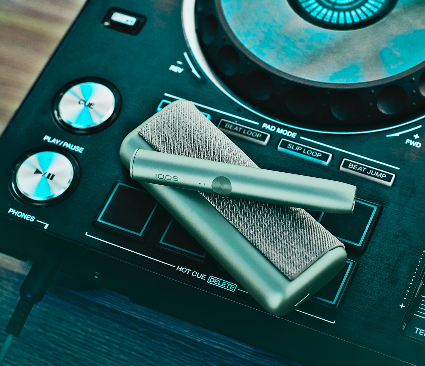 A Jade Green IQOS ILUMA PRIME Pocket Charger and Holder on a DJ's turntable. 