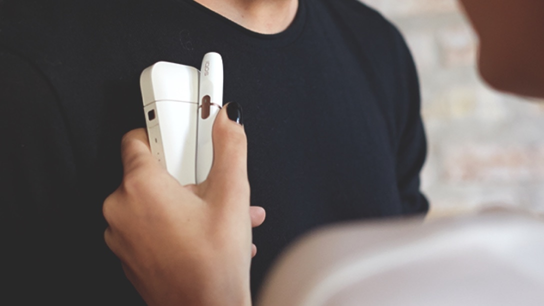 A white IQOS 2.4 PLUS in a person's hand.