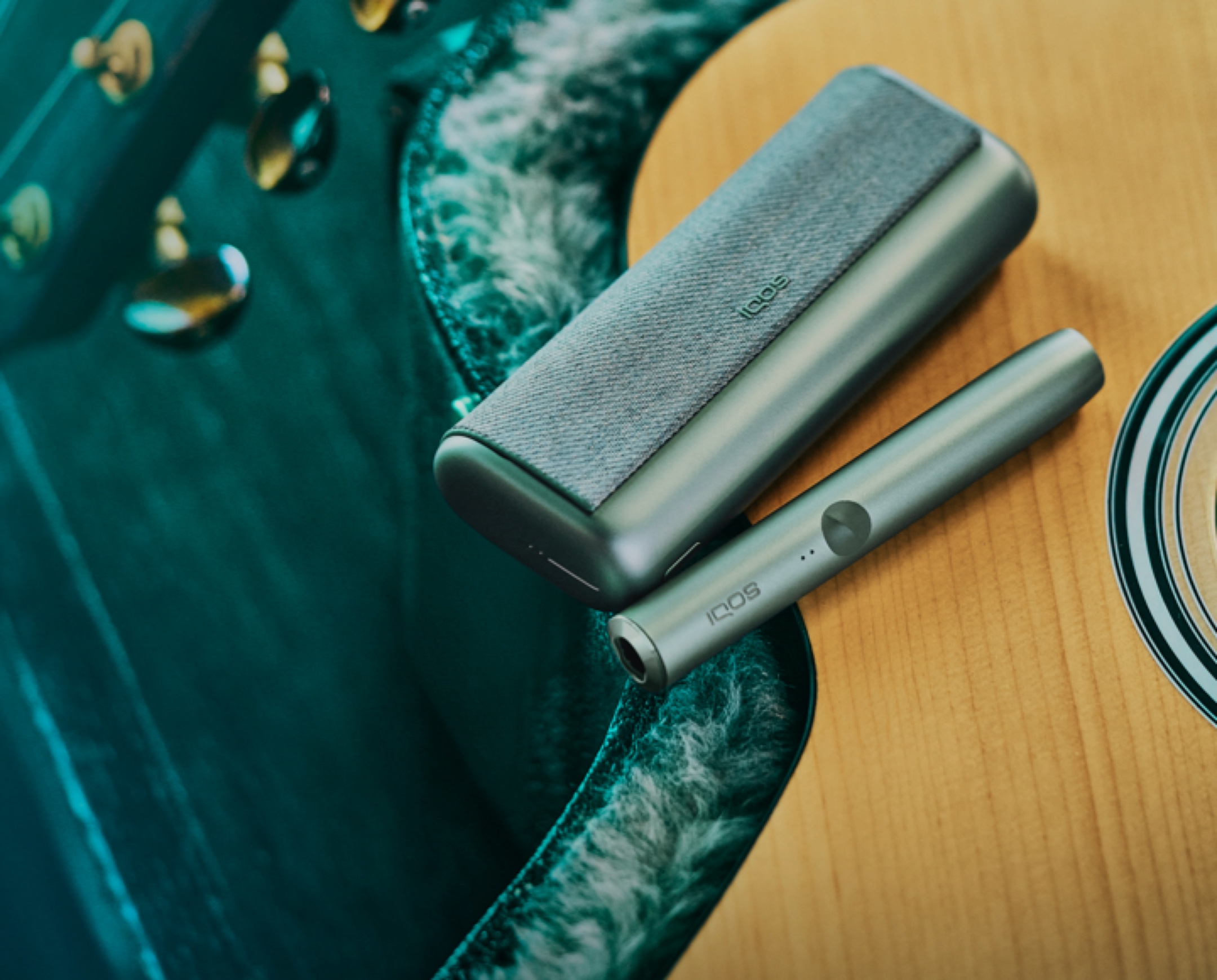 A Jade Green IQOS ILUMA PRIME Procket Charger and Holder on a guitar