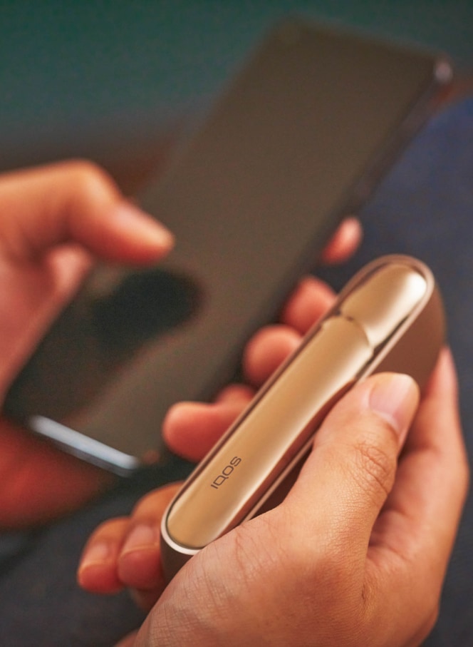 Man with a gold IQOS Duo and a mobile in his hands