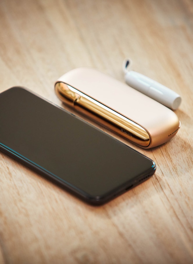 A mobile and a gold IQOS kit on a table