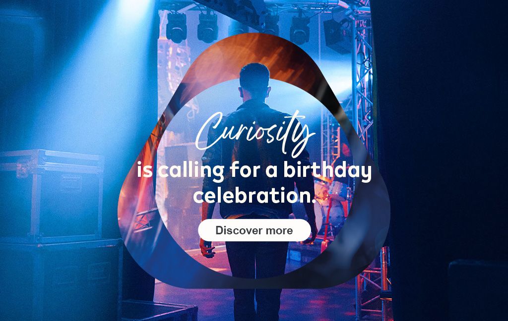 Person in leather jacket backstage under blue stage lights with the logo overlay.